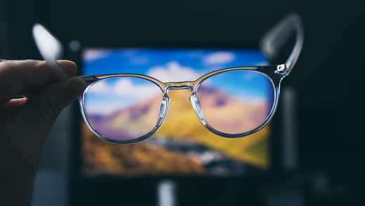 Transparante blauwlicht filter bril vastgehouden voor een computerscherm om blauw licht te blokkeren en oogvermoeidheid te verminderen